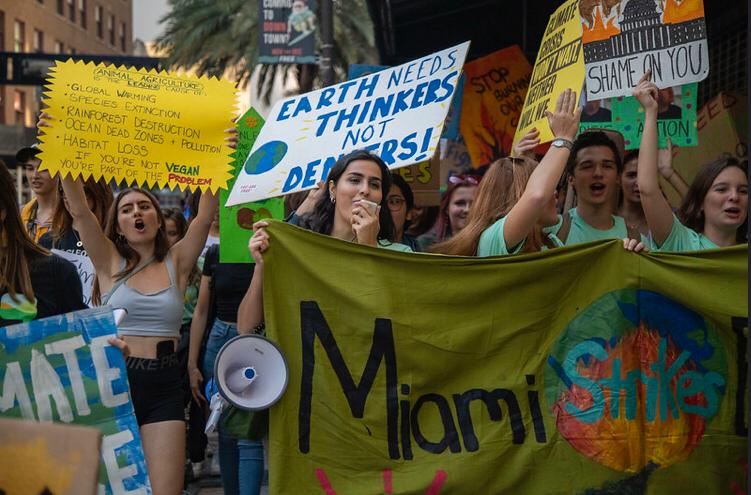 Miami protestors hold up their signs proudly as they stand up for climate change action.