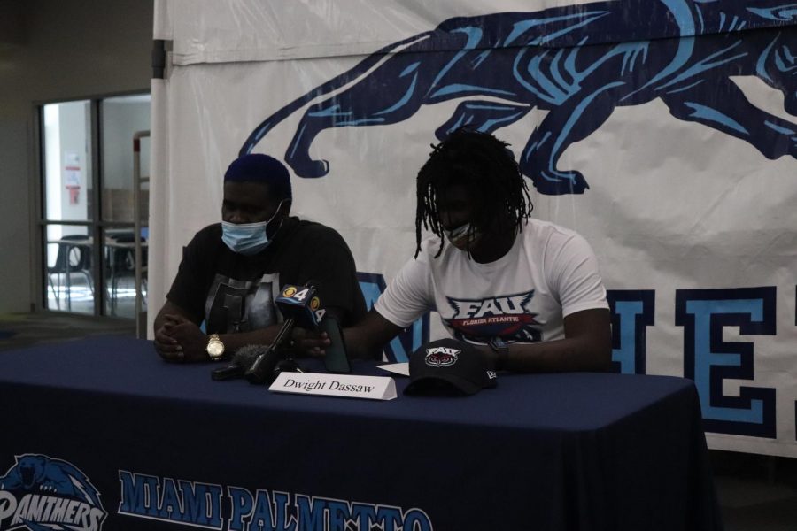 Dassaw sits with his father and shows off his Florida Atlantic University gear after officially signing on.