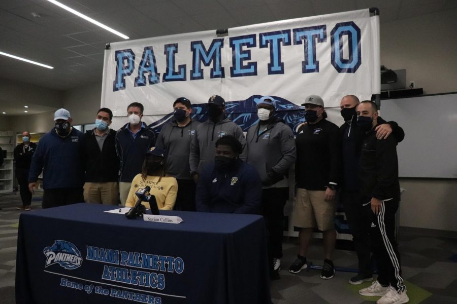 Collins poses for a picture with the football coaching staff. 